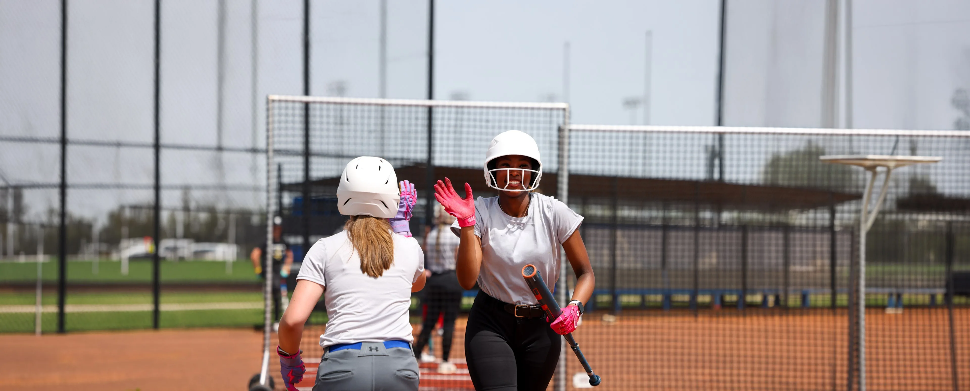 Softball players high-fiving after an at-bat