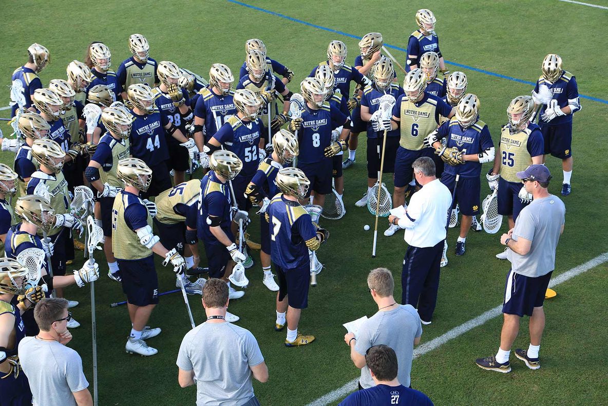 A lacrosse team huddled with their coaches