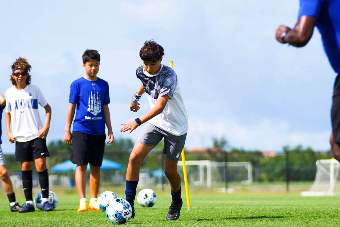 Young soccer campers running a ball-control drill with a coach