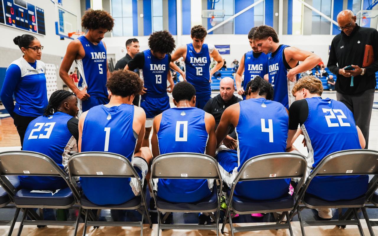 IMG Academy men's basketball team in a huddle on the bench