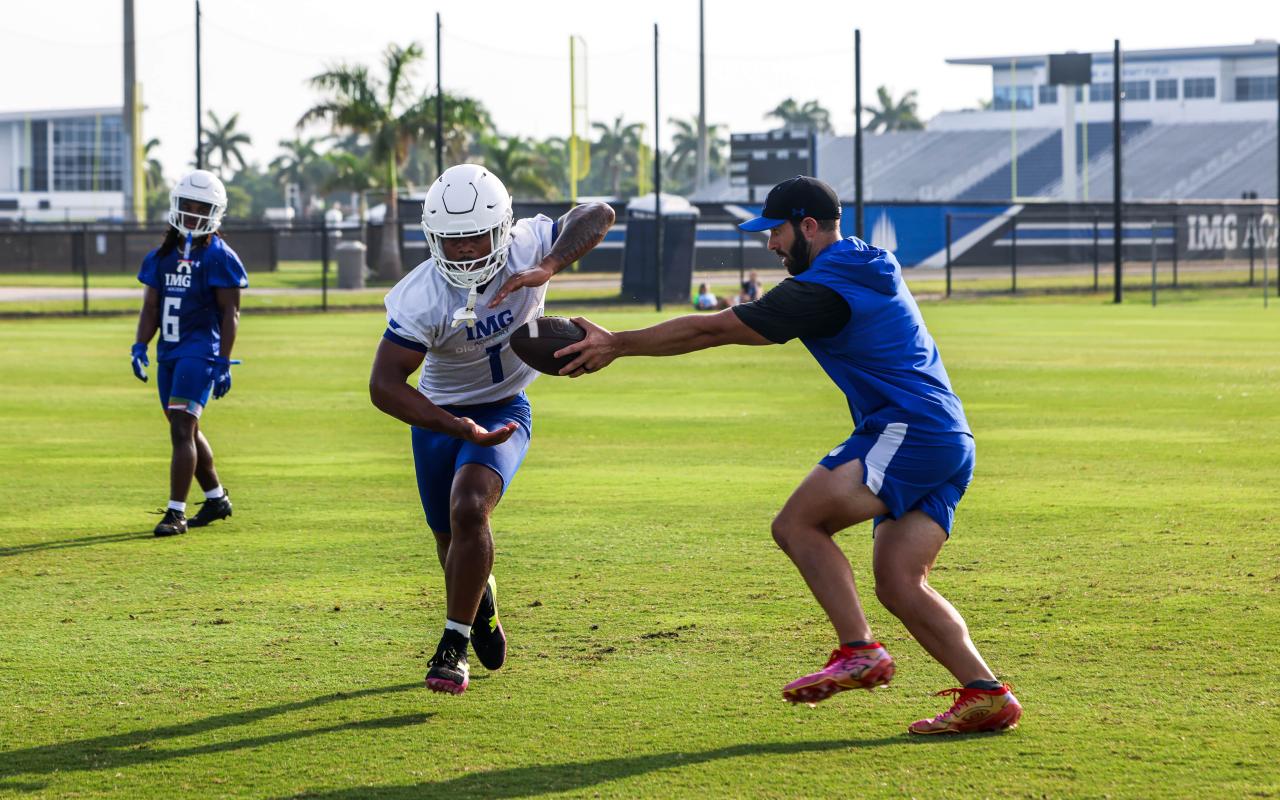 A coach and student athlete running a football drill during practice at IMG Academy