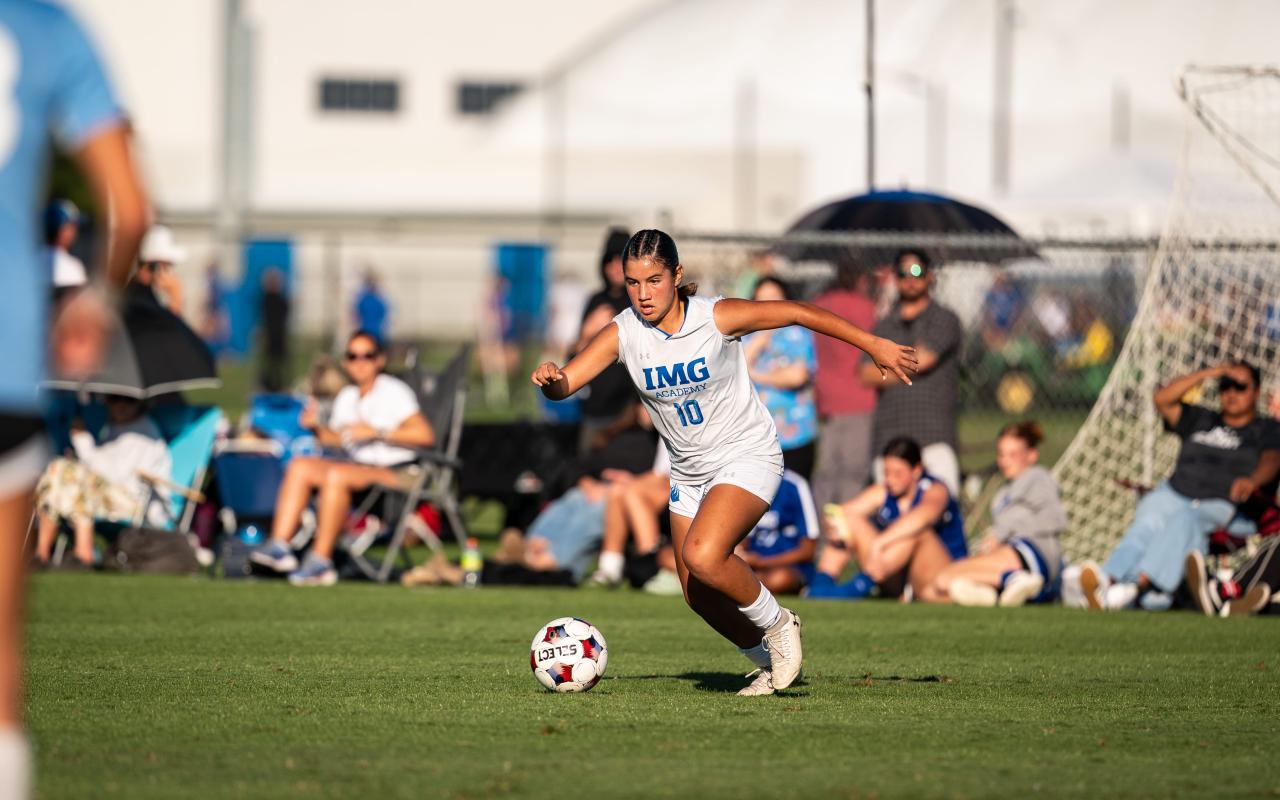 Female IMG soccer athlete dribbling the ball down the field