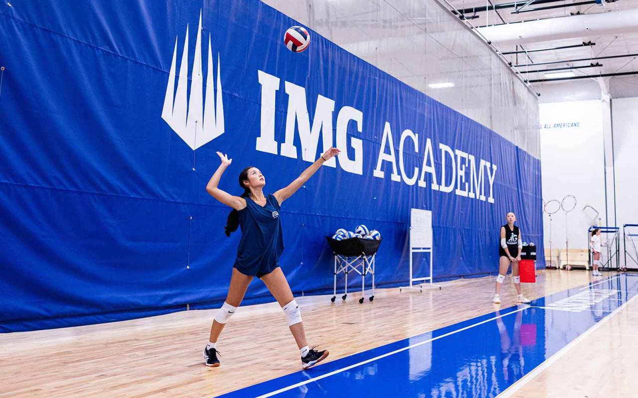 A female athlete practicing serving the volleyball at an IMG Academy Volleyball Camp